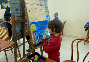 Chłopiec maluje obraz na sztaludze